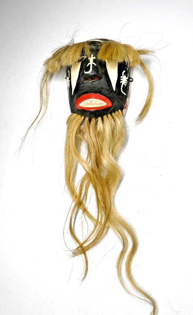 A Yaqui Indian Pascola mask with long beard and brows: A mid to late 20th century carved wooden festival mask with red, black and white painted designs as well as long hair attachments from the forehead and chin. The Yaqui Indians, who have lived in the M