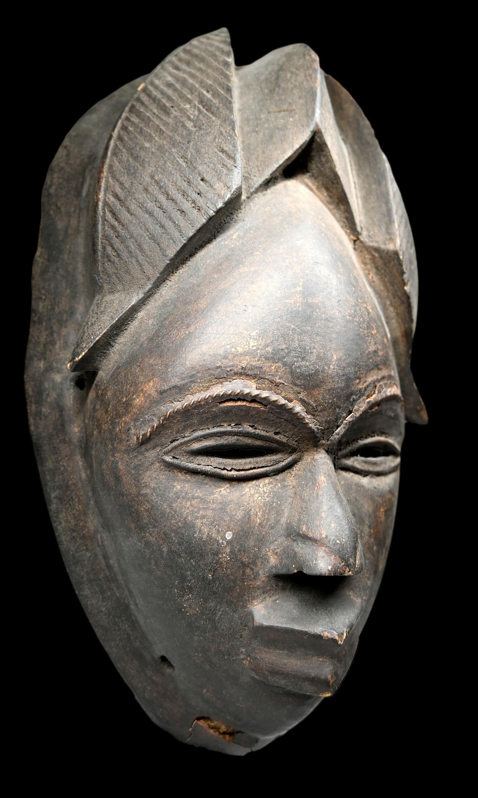 Vintage Ibo Mask: A carved wooden mask with some age and wear. Ibo or related peoples, Nigeria, Africa. The mask measures 13 inches tall. Provenance: Ex Roth Collection, CT, USA.