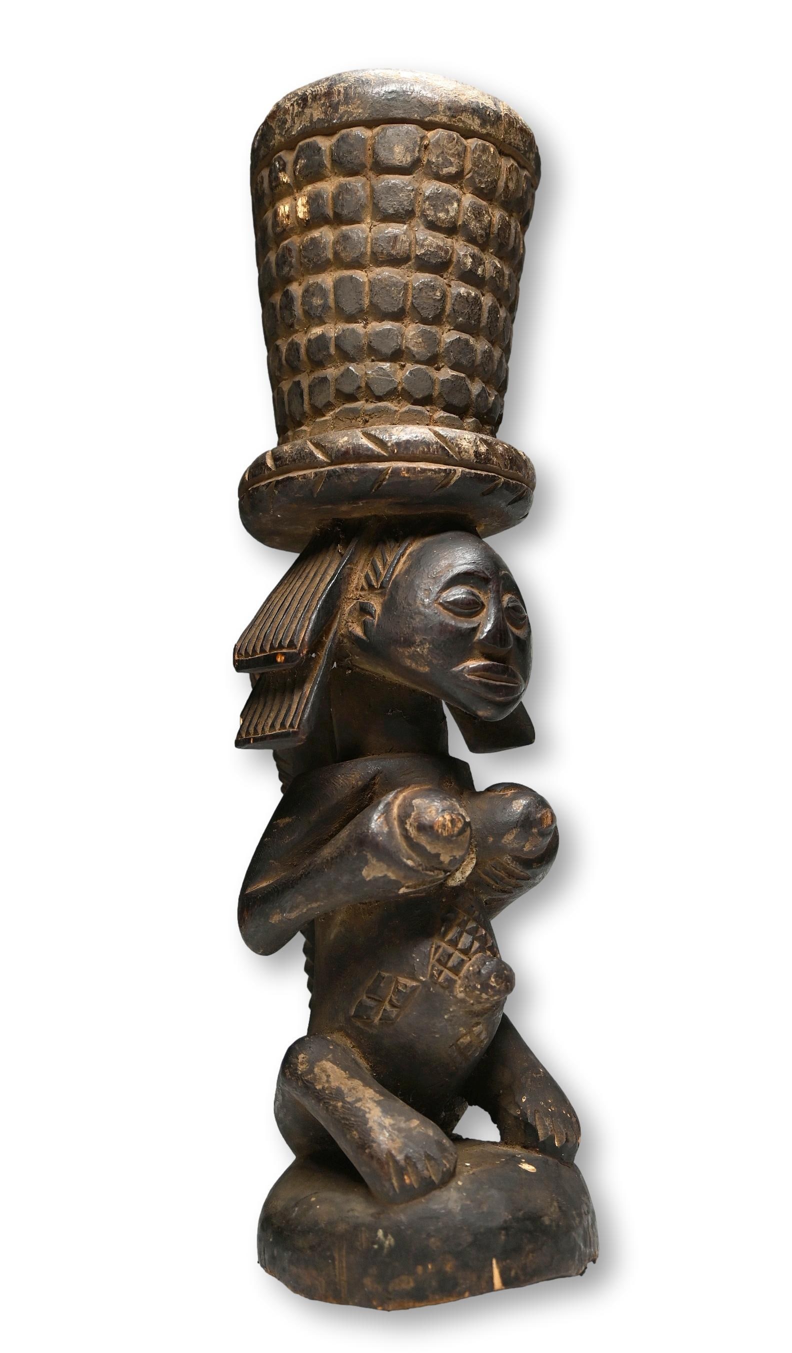 A Luba Tobacco Mortar: A very finely carved wooden sculpture of a female shown holding her breast in a fertility pose, with classic cascading coiffure and stylized form, raised scar designs on abdomen and an overall well ha