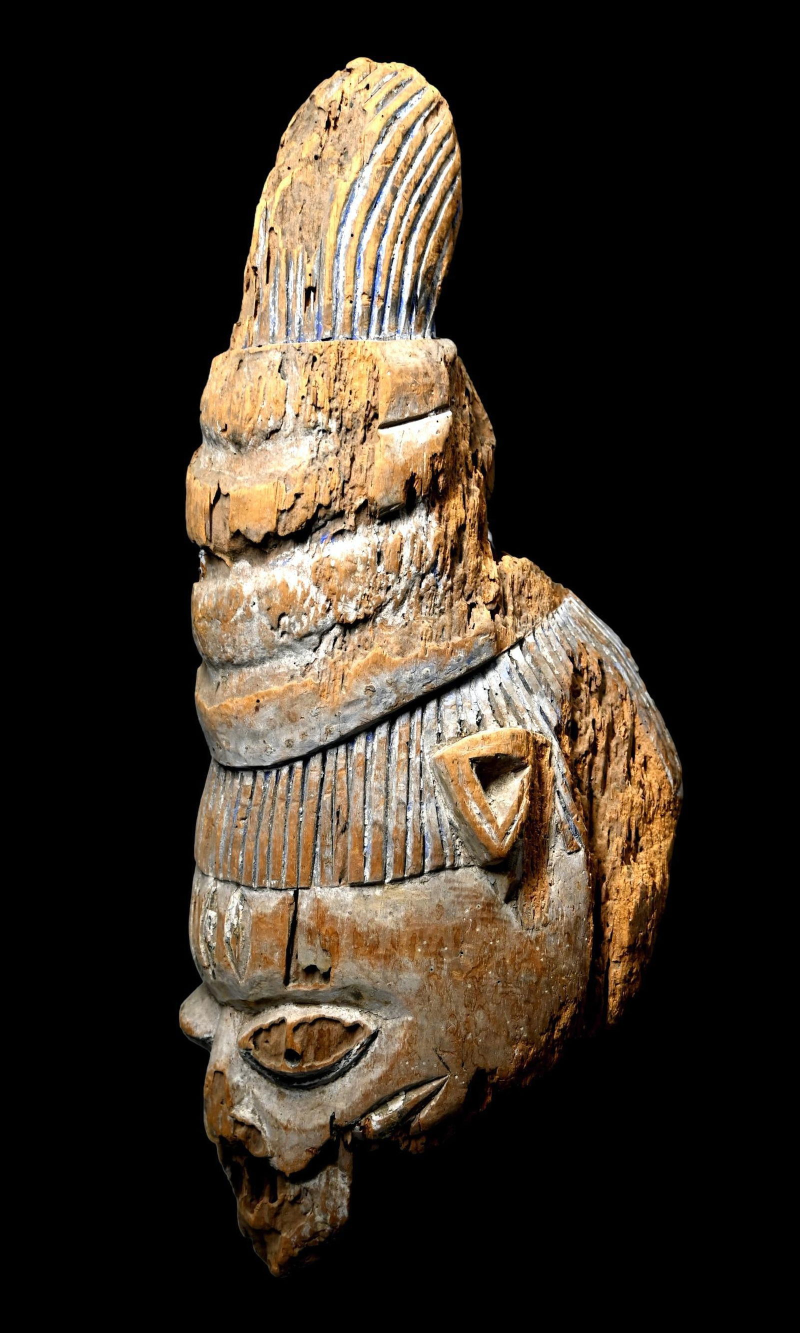 Eroded Old Yoruba Gelede Mask: A very old and eroded, weathered and worn ceremonial mask, with remains of blue mineral pigments and obvious age and exposure to the elements. This mask measures 17.5 x 8 inches , a display stand can