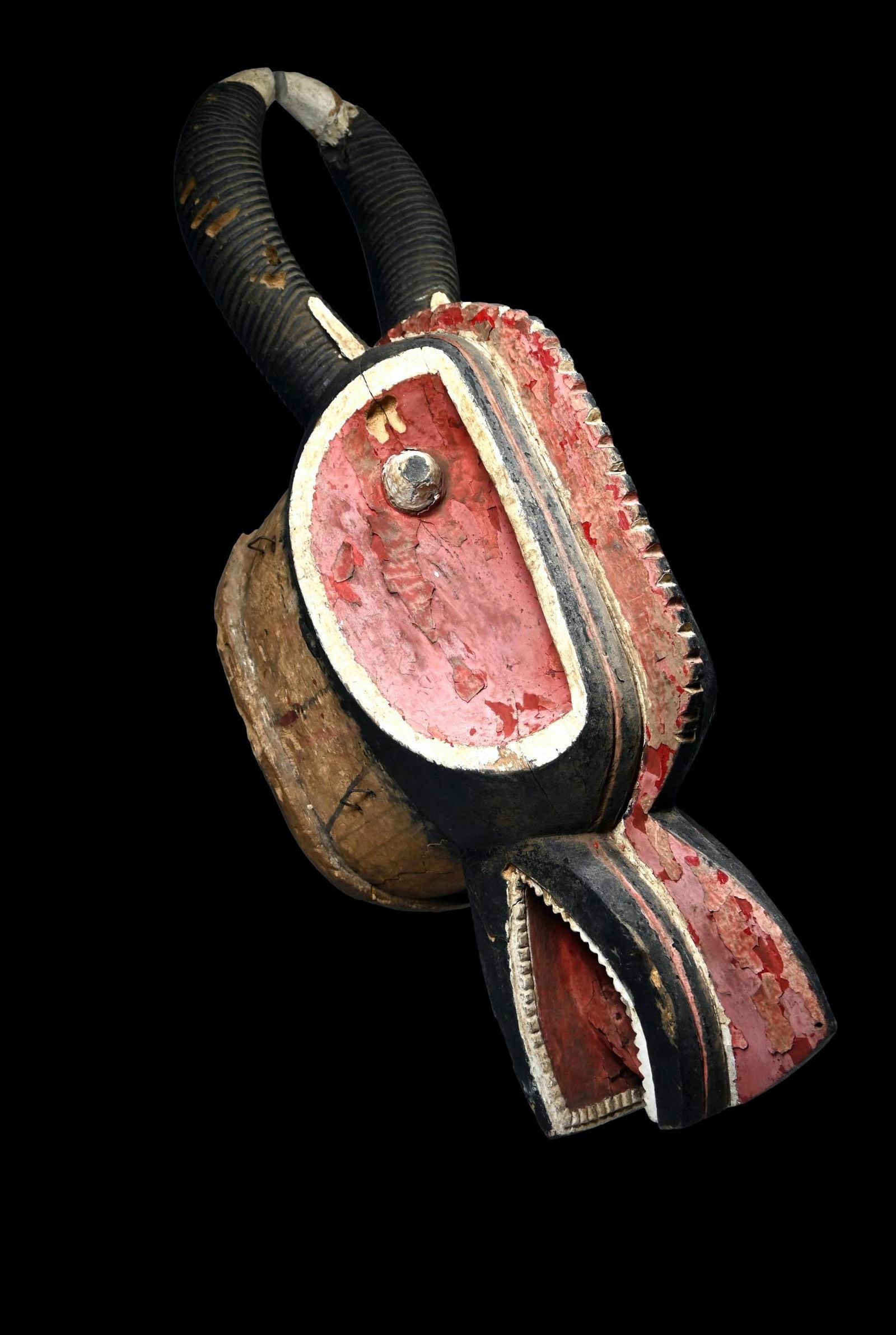 A Baule Goli Glin Mask: A large carved wood and painted helmet style mask which bears some of the classic details of a bovine head, horns extending from the back and an open jaw with a prominent tongue and teeth. The small h