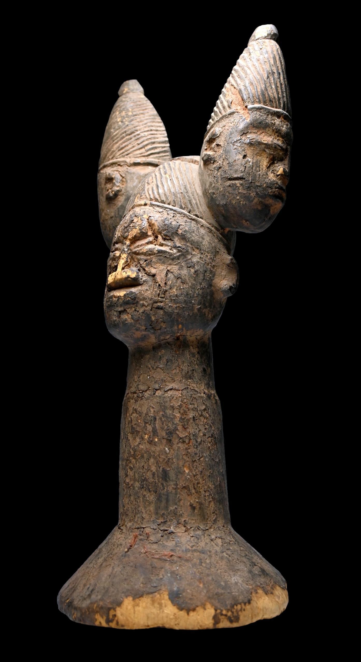 A Yoruba Shango Cult Effigy: A very old carved wooden shrine effigy or possibly a scepter dedicated to the Yoruba deity Shango. The sculpture of an ancestor with two janus form spirit heads on top, all carved from a single piece