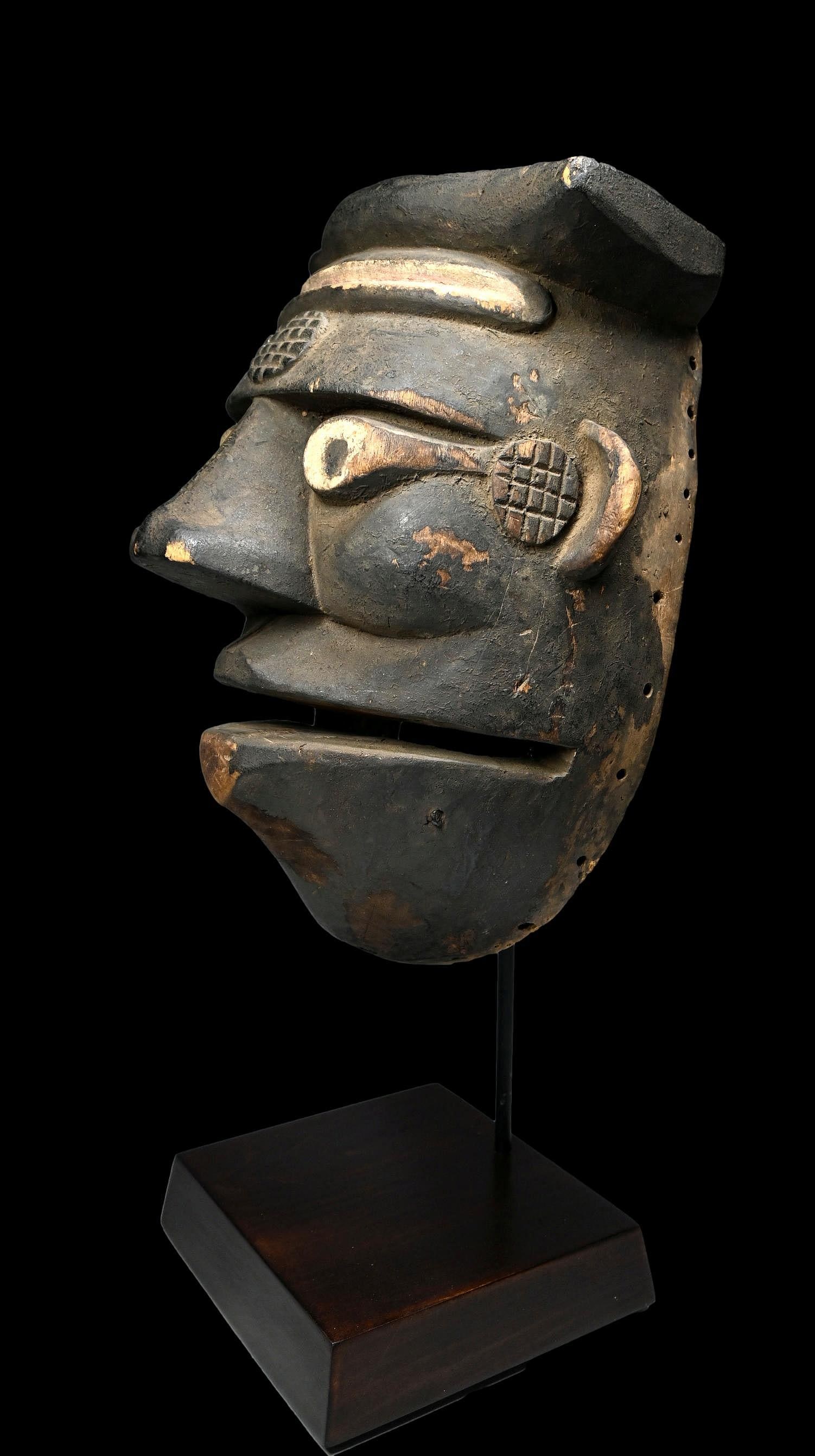 A Large Ogoni African mask: A large carved wooden mask with raised scar designs kaolin clay pigment accenting the eyes and forehead scars, well handled and weathered with an encrusted and painted black surface. Men and boys danc