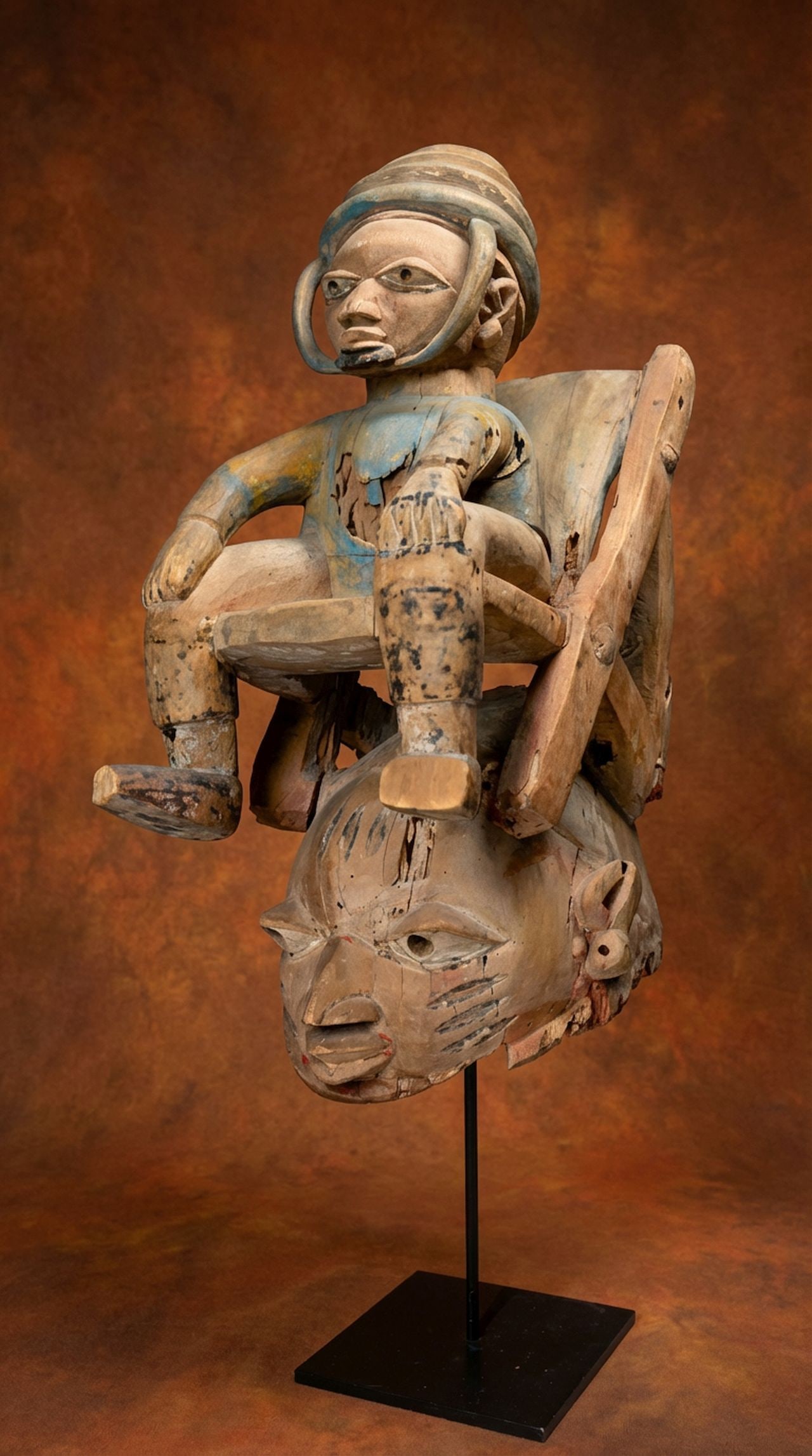 A Yoruba Gelede Mask: A finely carved and quite charming old festival mask featuring a seated male effigy on top along with folding chair. The mask has great age and some obvious wear , what remains is strong and stable. T