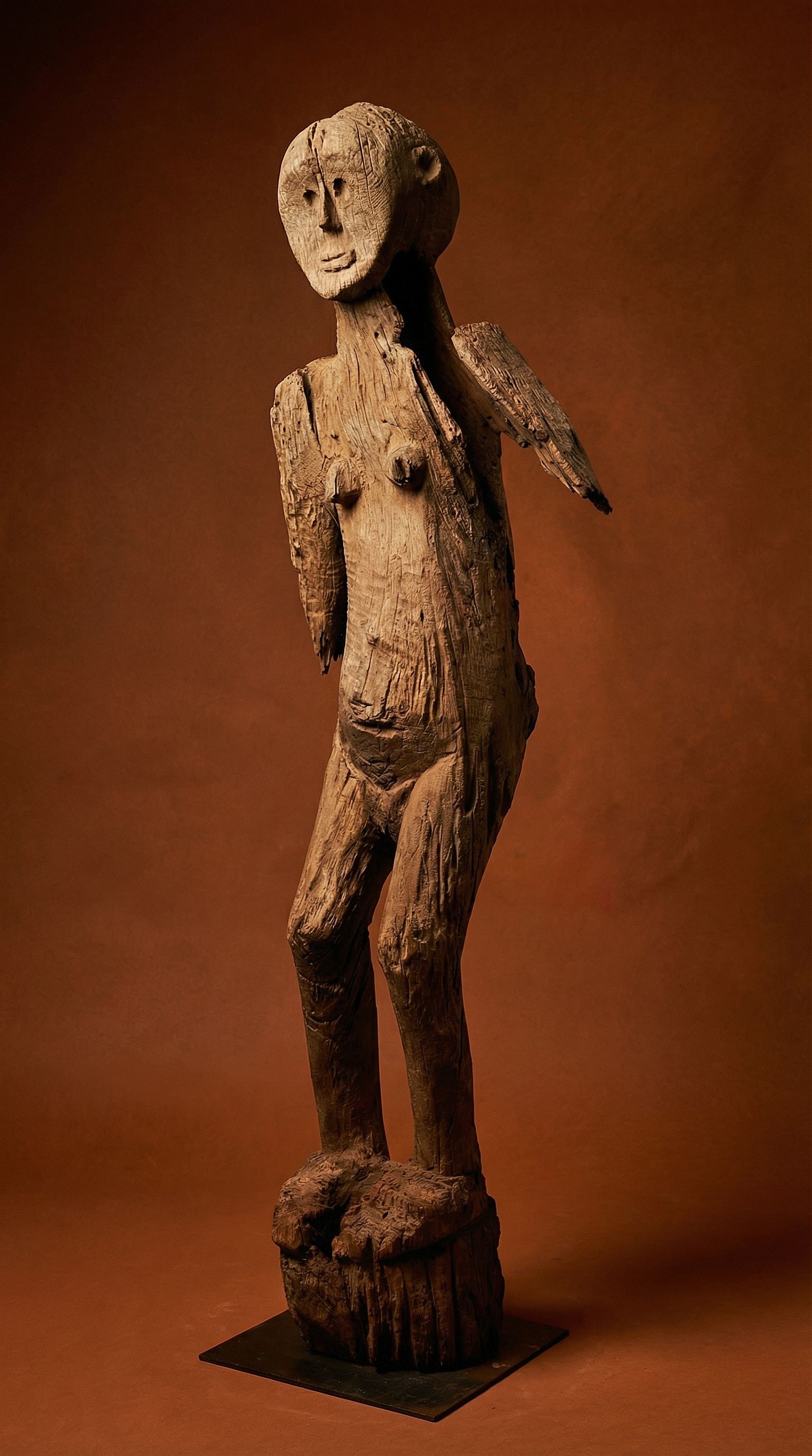 A Rare Bongo Monumental Ngya Sculpture: A tall carved wooden anthropomorphic female effigy sculpture with a heavily eroded and weathered surface, hollowed out core and loss to the arms. The figure likely dates to the mid 19th century or old