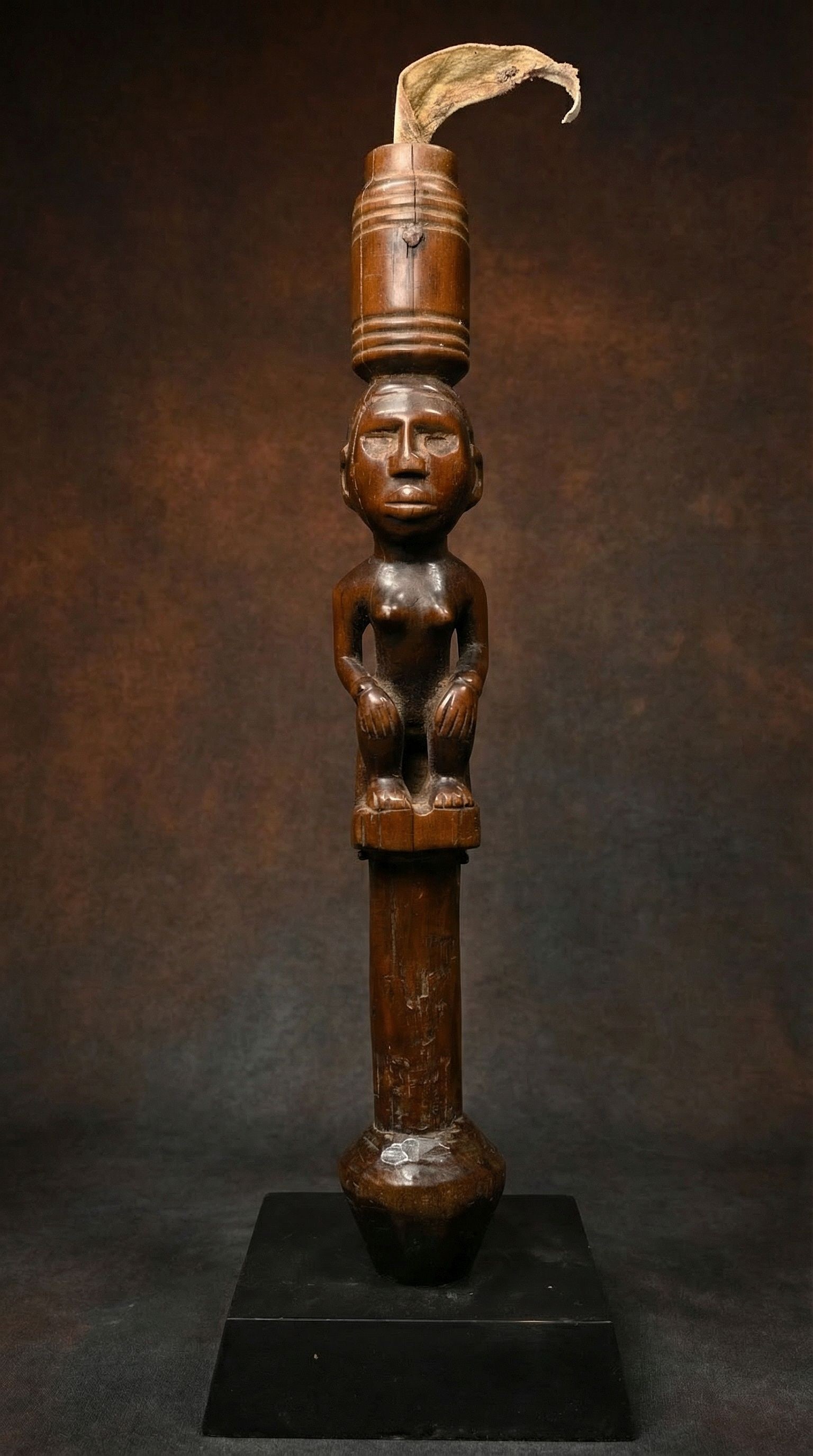 A Bakongo Fly Whisk Handle Ex J. Camp Gallery: A Finely carved wooden handle featuring a seated female ancestor, with incised linear designs and a deep well handled honey colored surface patina. The remains of an animal tail are still present on t