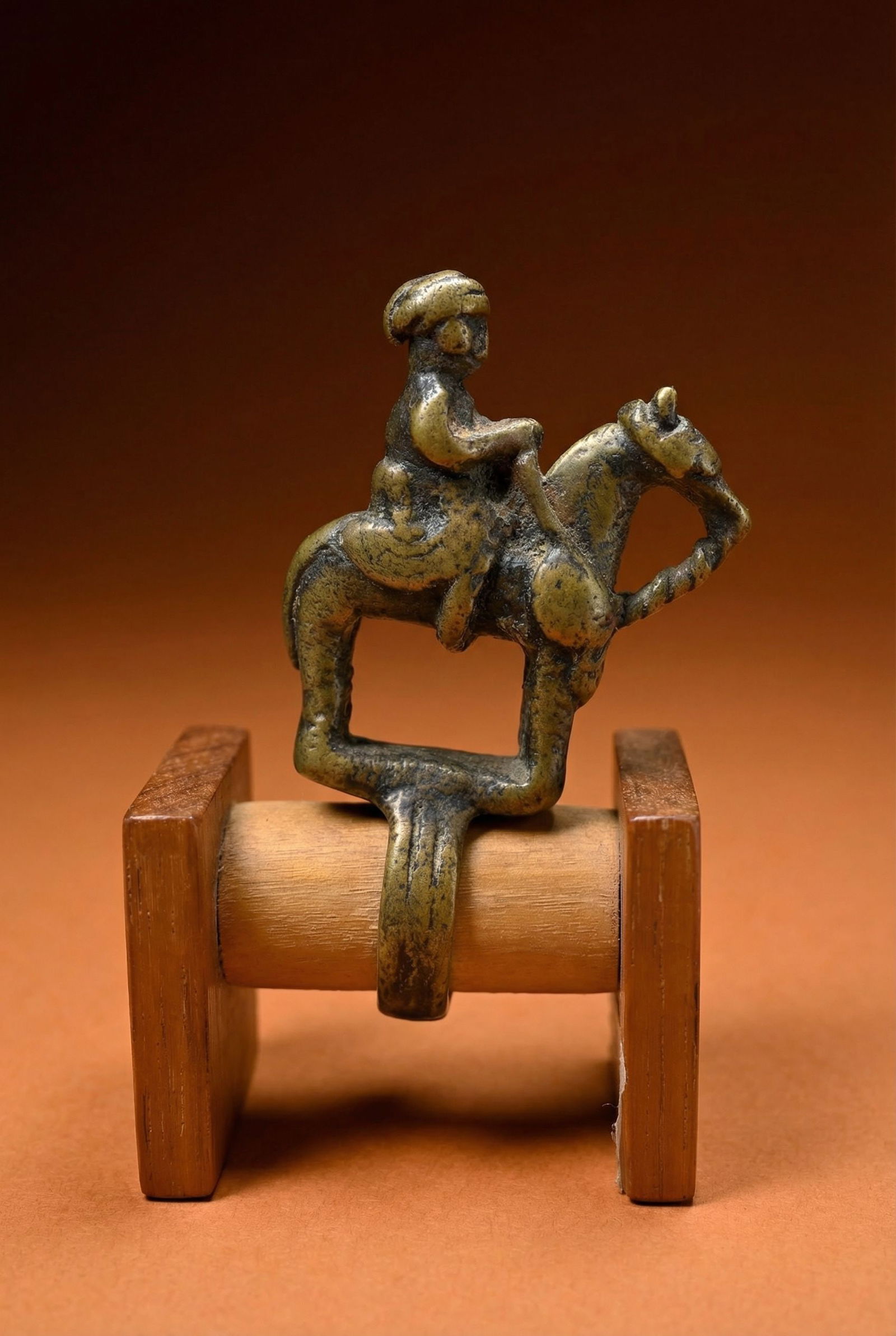 A Dogon Bronze Equestrian Ring: A finely cast bronze ring featuring a Horse and ride and some semi circular designs. This Ring measures 2 5/8 x 1.75 inches deep, 3.25 inches tall on custom wooden base. Dogon peoples, Mali, West Afri