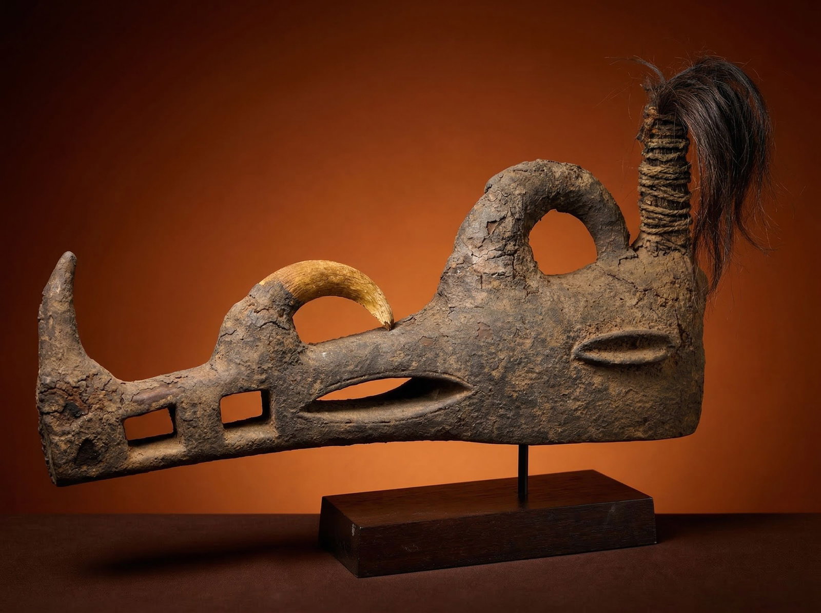 A Bamana Komo Mask: A carved wooden helmet style mask embellished with animal horns and plant fiber. Such masks known as Komo are linked to Power associations and the control of Nyama, or sacred energy through sorcery an