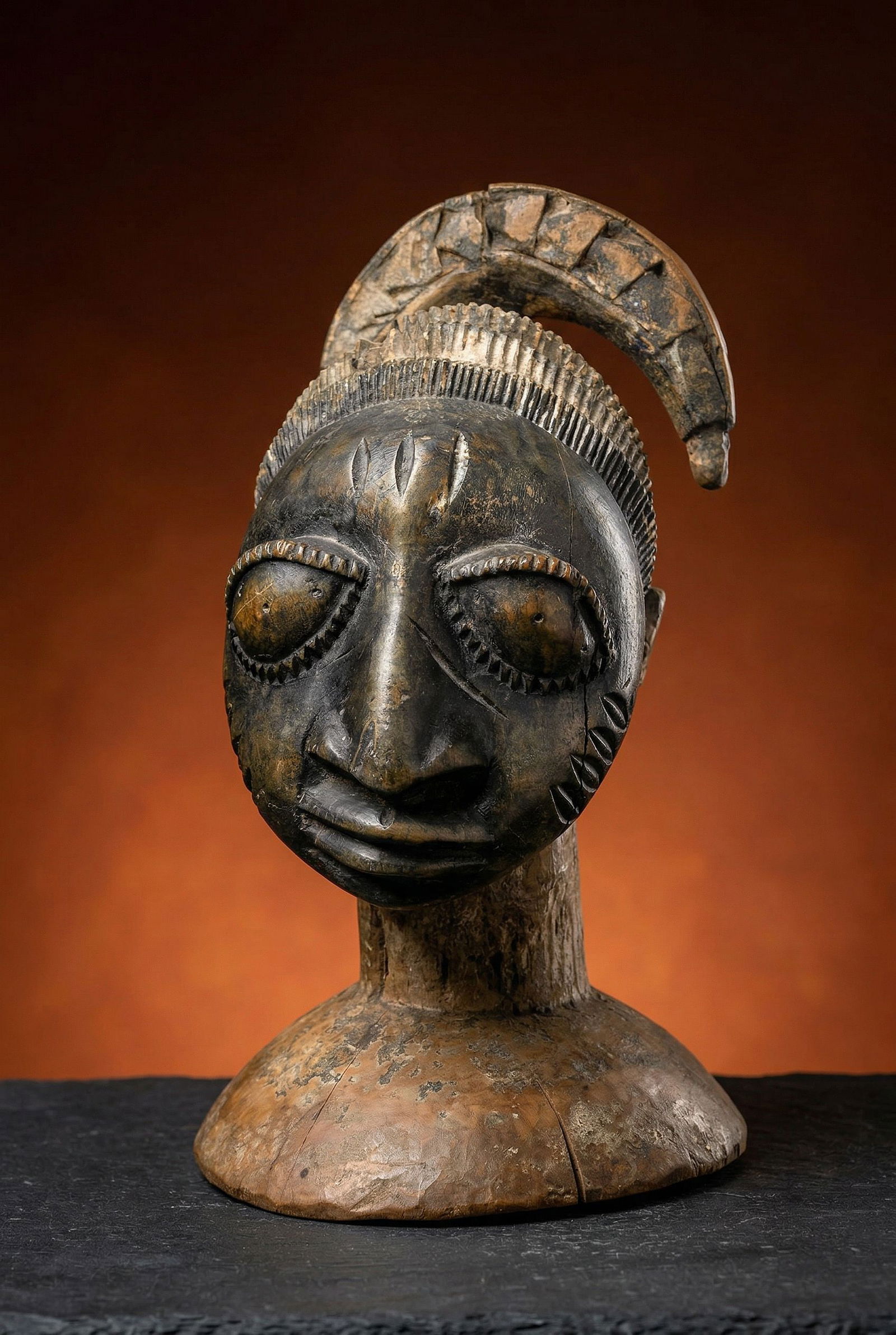 A Yoruba Dance Crest of Egungun: A carved wooden dance crest / cap with a highly stylized image of the god Egungun with the traditional long plait of hair hanging to one side. This ceremony commemorates in particular, the important a