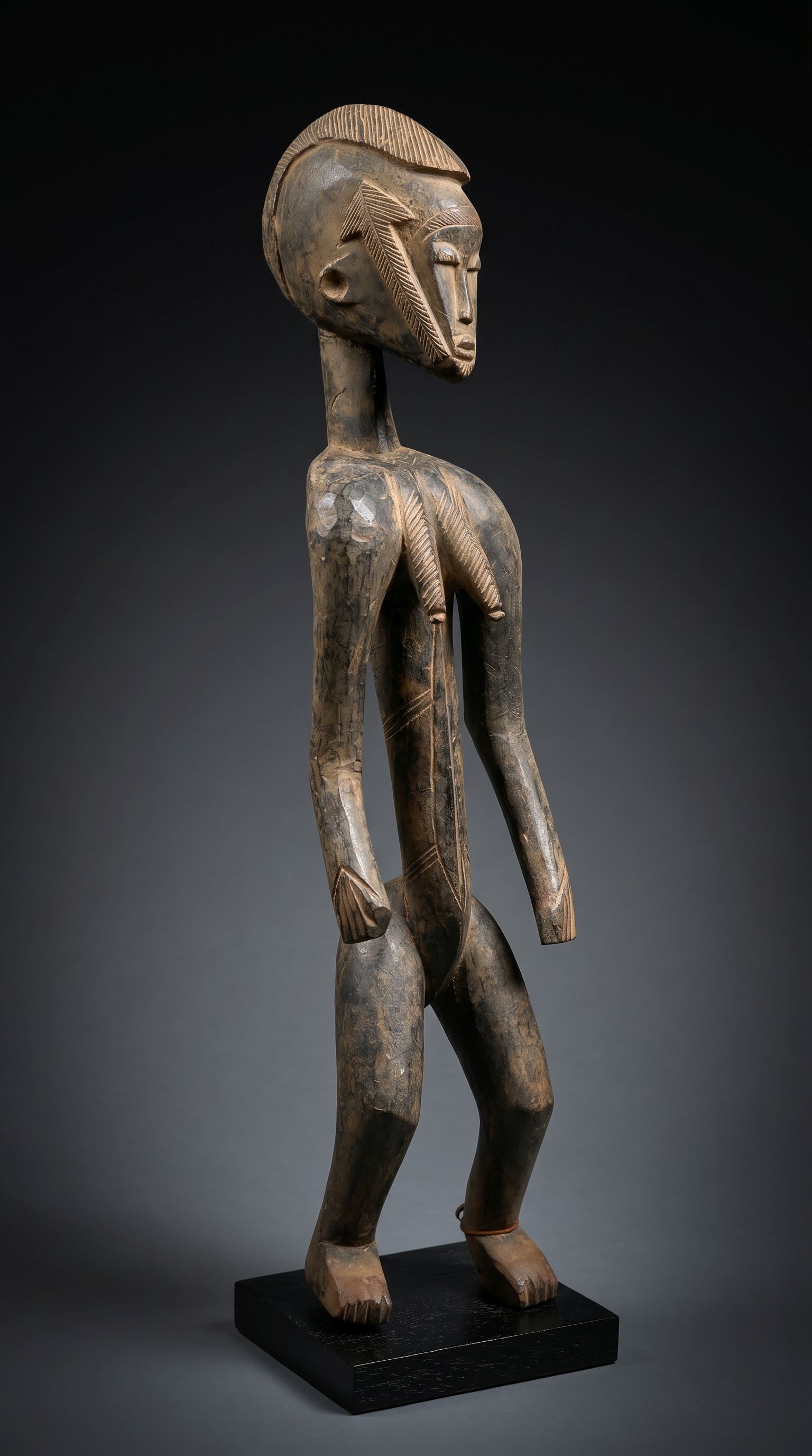 A Bamana Female Sculpture: A wonderfully stylized female effigy with bold geometric raised designs, carved coiffure and exaggerated form, well worn. Bamana / Bambara peoples, Mali, West Africa. The sculpture measures 28 inches 