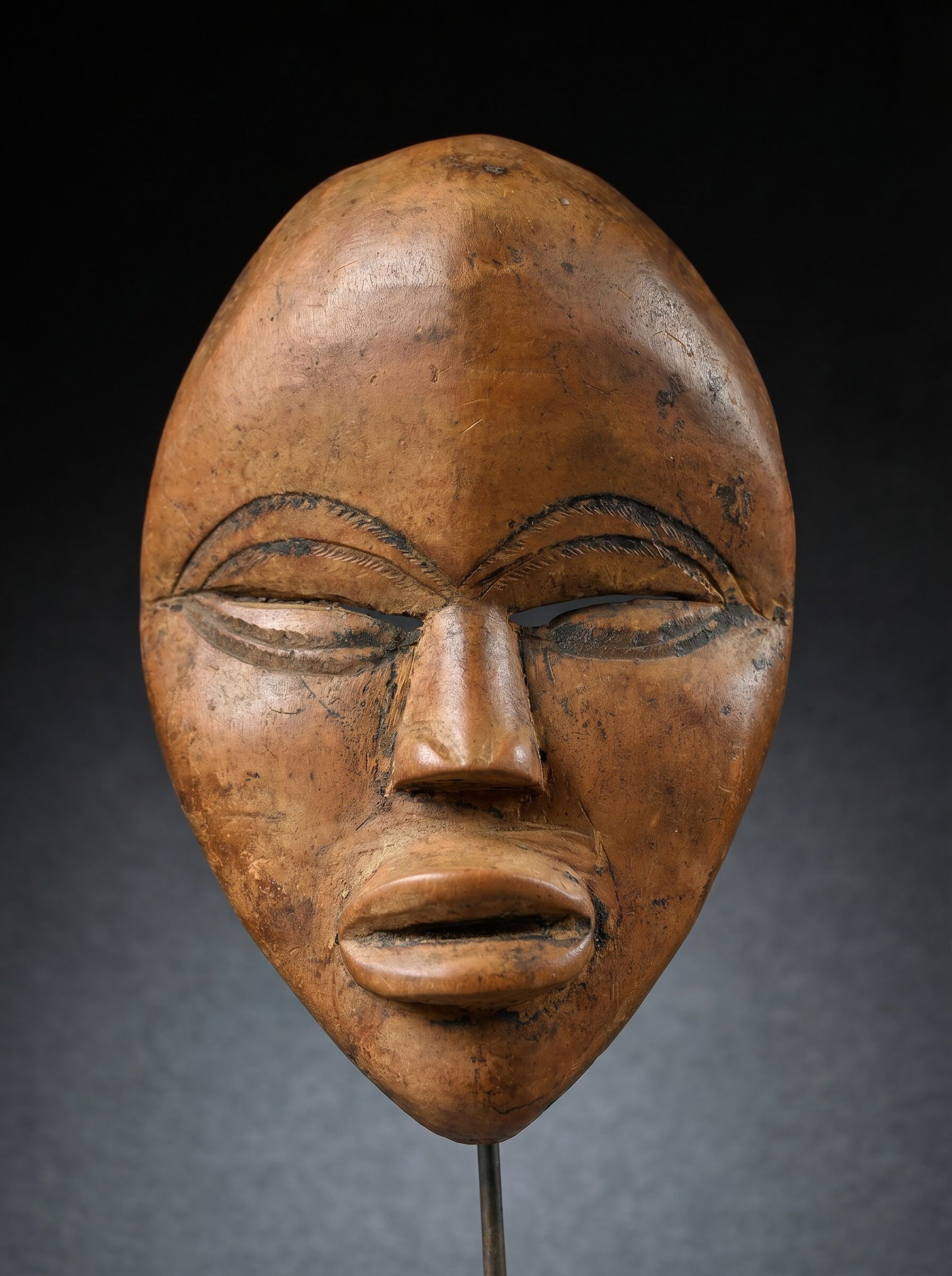 A Dan Passport Mask: A diminutive carved wooden mask in classic style, well handled and worn surface patina suggesting field use as a traditional "Passport" Mask or MAS as known locally. A small example carried by the own