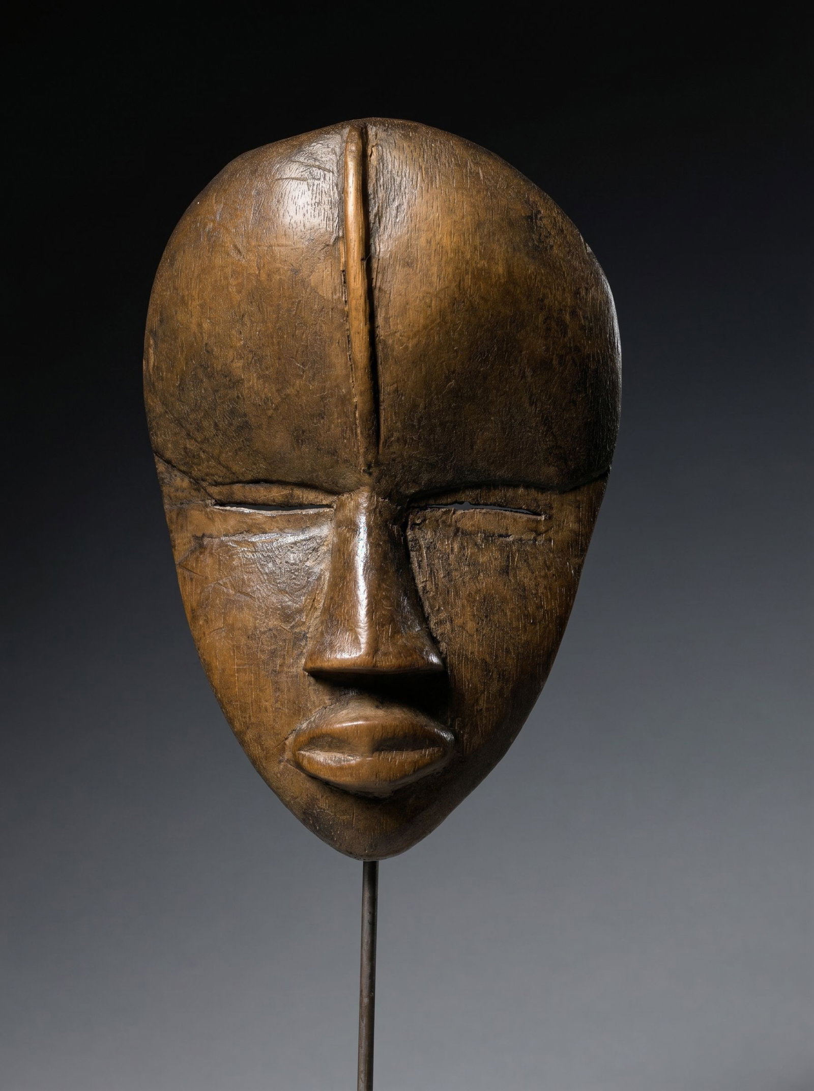 A Fine Dan Passport Mask: A diminutive carved wooden mask in classic style, well handled and worn surface patina suggesting field use as a traditional "Passport" Mask or MAS as known locally. A small example carried by the own