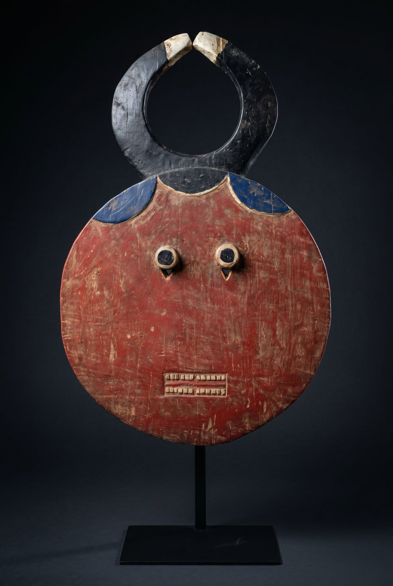 A Large Baule Kpele Kpele Mask: A large carved wooden ceremonial dance mask with stylized geometric form and painted designs. The kpele kpele mask represents the junior male element in a series of four mask types that appear in pair