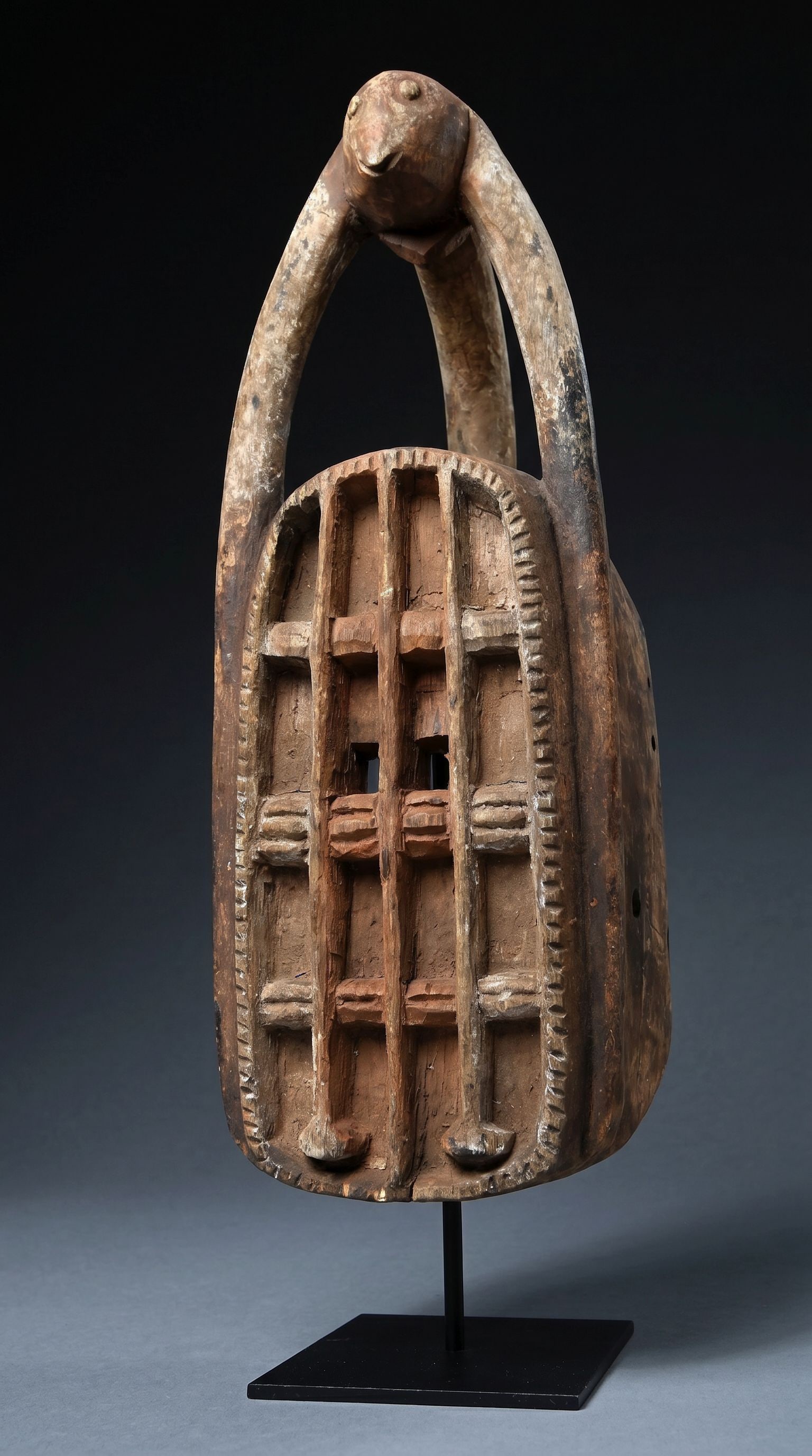 A Dogon White Monkey Mask: A carved wooden ceremonial dance mask featuring a highly stylized white monkey known as Iminia Omono. This monkey is carved in an openwork style as well as a wonderfully abstract face that is reminisc