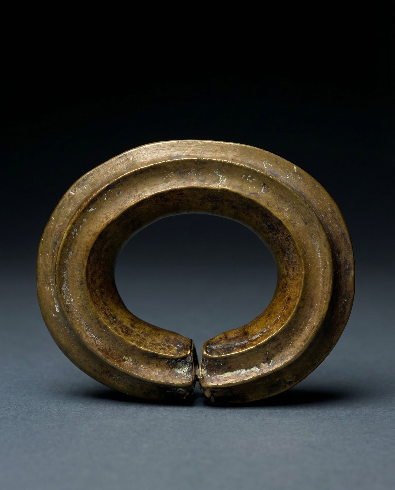 A Dan Bronze Currency / Anklet Field Collected 1960s: A heavy cast bronze anklet or currency form with strong linear design and well handled surface patina. The Bronze measures 5 x 4 x 1.25 inches thick. Dan peoples, Liberia, West Africa. Provenance: Fie