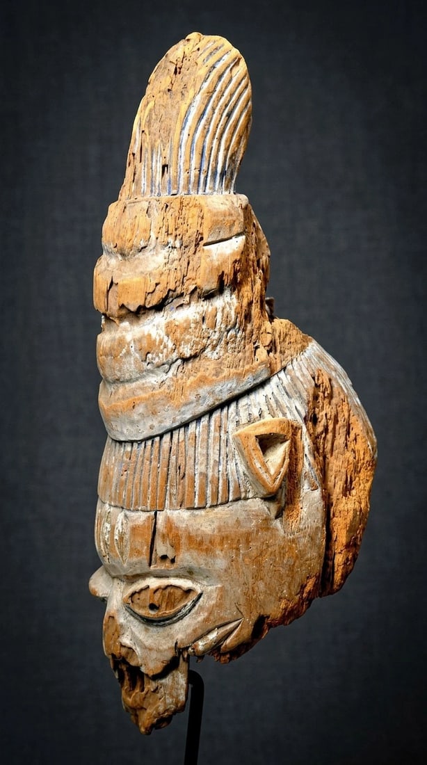 Eroded Old Yoruba Gelede Mask Ex Stirner Collection: A very old and eroded, weathered and worn ceremonial mask, with remains of blue mineral pigments and obvious age and exposure to the elements. This mask measures 17.5 x 8 inches. There is no display s