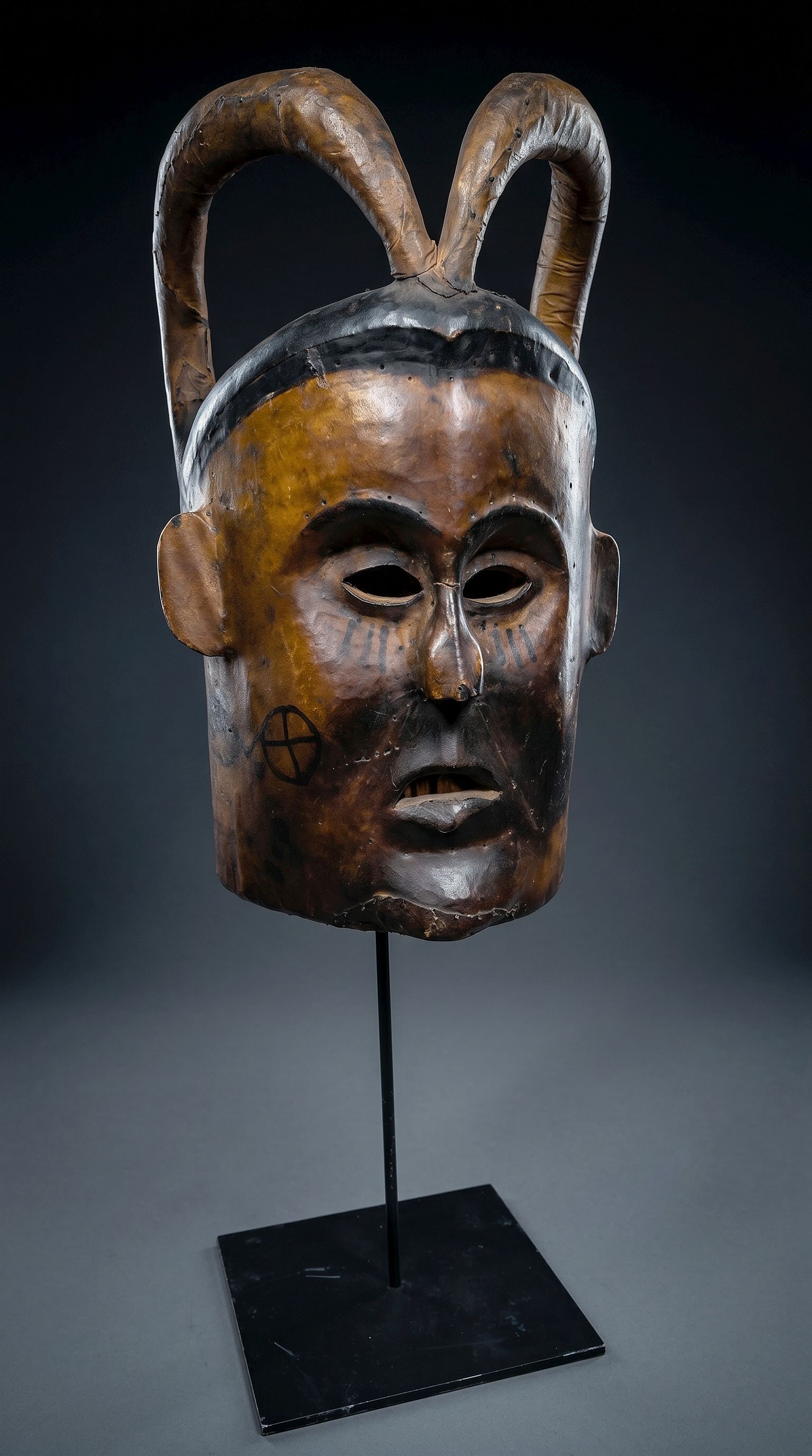 A Ekoi Ejagham Helmet Mask: A large and stylized helmet mask with two tall curved horns and painted designs. The entire mask is covered in tightly adhered animal skin. Ekoi or Ejagham peoples, Cross river region, Nigeria, Africa