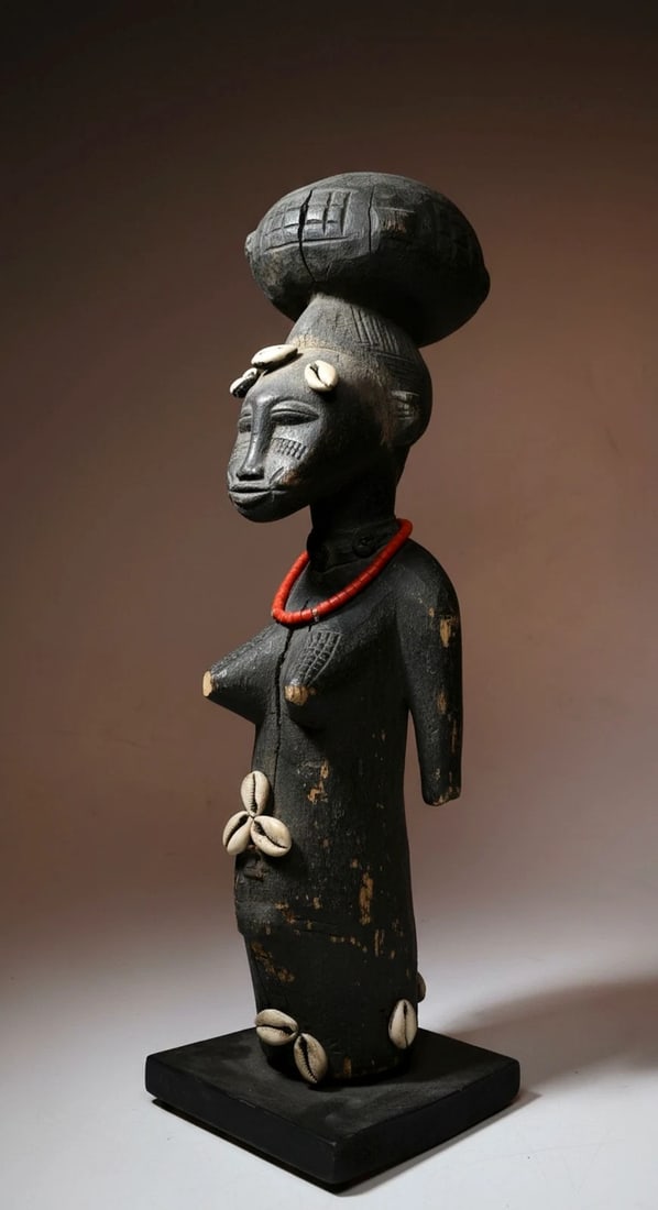 A Senufo Divination Idol: A dark and highly stylized carved wooden female effigy with a well handled surface , loss to both arms and legs yet worn smooth and continued to be used as a diviners tool, a medium to the spirit