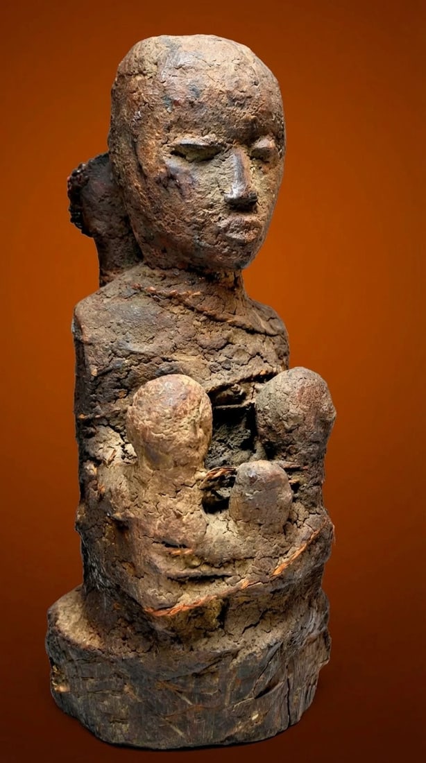 A Fon Vodun Shrine fetish: A Carved wooden shrine idol with two or possibly three small children or spirits, bones and a heavily encrusted surface of ritual offerings, the figure is bound with rope to bind a spirit into service