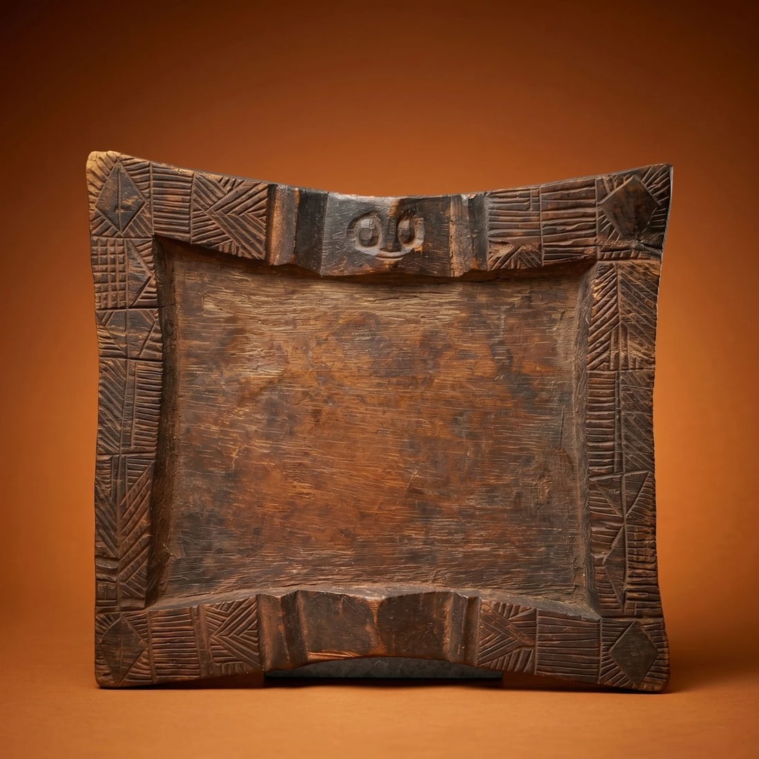 A Yoruba Opon Ifa Divination Tray: A Yoruba Opon Ifa Divination Tray.A Carved wooden flat tray with carved and raised various motifs relating to Yoruba life and spirituality, the Yoruba Trickster god Eshu face is on top of the tray. Th
