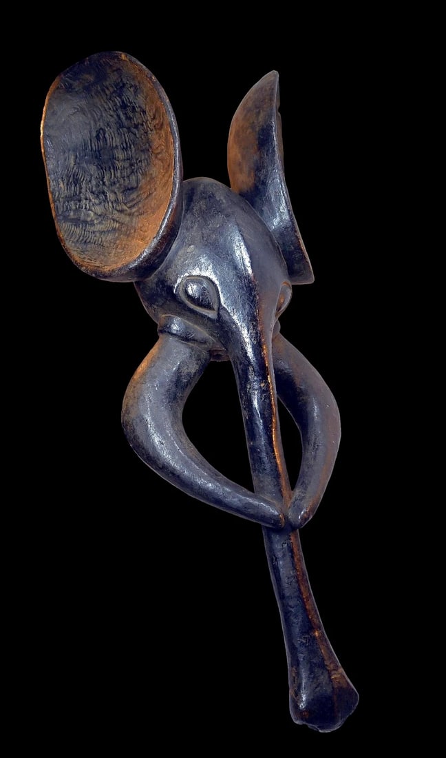 A Babanki Elephant Mask: A carved wooden cap like zoomorphic mask with well handled deep patina from field use. Head crests allegorizing the head of an elephant that were worn during performances put on by powerful associatio