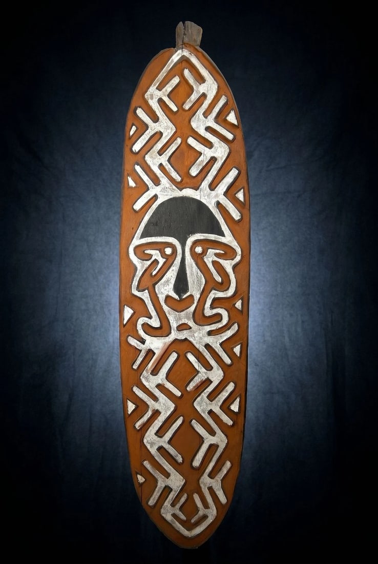 A Kikori Gope Board: A Kikori area spirit board (Gope); Gulf province Papua New Guinea. (C. 20th Century) A tall carved wooden panel of typical form for the type, the board in a rust color with black and white designs whi