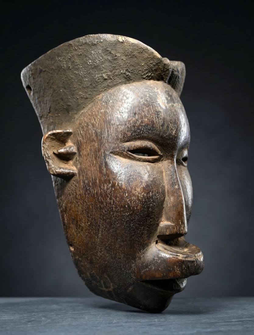 A Makua African mask: A carved wooden mask with stylized swept back coiffure and traditional Lip Plug and a well handled surface patina. Makua or related peoples, Mozambique, central Africa. The mask measures 9.5 x 7 inche