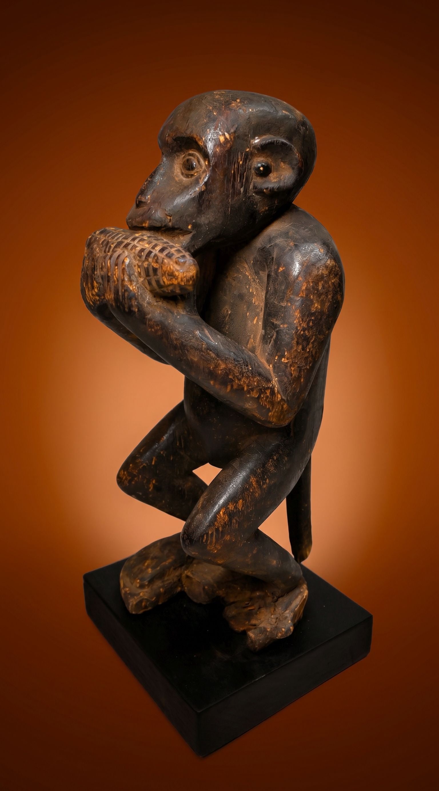 A Monkey Eating Corn Sculpture: A vintage sculpture of a monkey eating corn with realistic features and a well handled patina, weathered surface. Bulu or related ethnic group in the Cameroon grasslands region, West Africa. The Monke