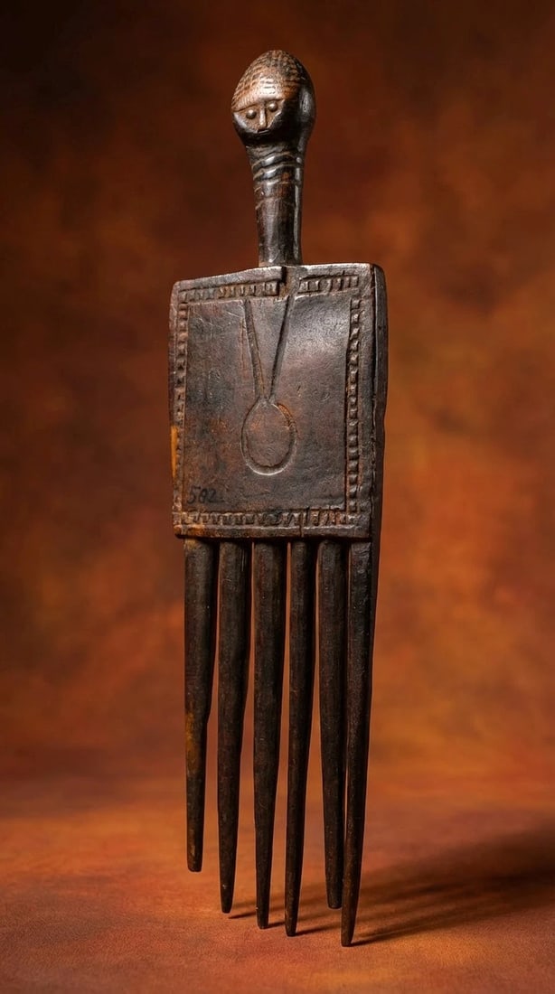 A Fine Old Baule Comb: A fine old carved wooden janus comb from the Baule peoples of the Ivory Coast, West Africa. An classic example and masterwork of carving, note the carved cross necklace adorning the combs carved woode