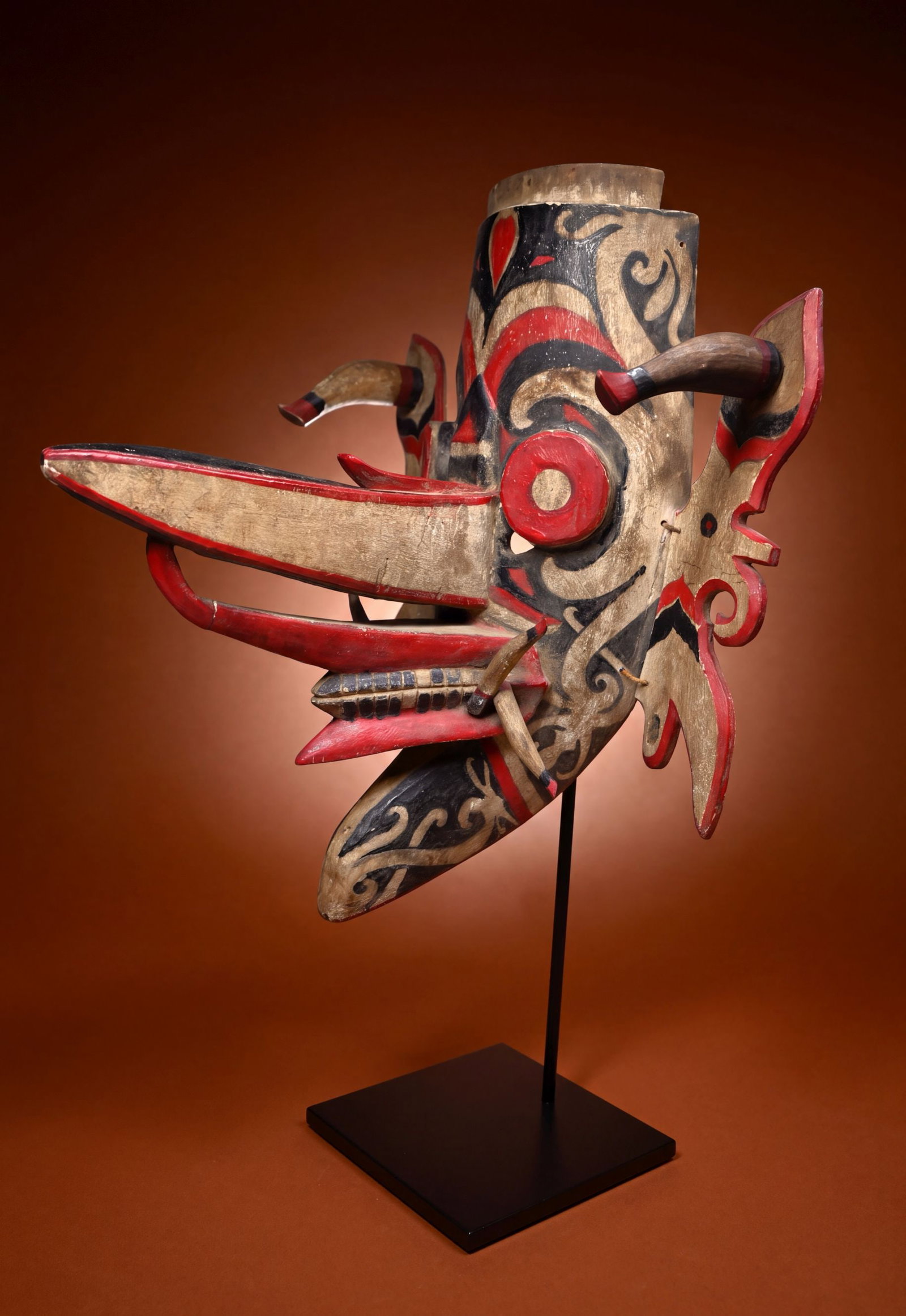 A Dayak Hudoq Ceremonial Mask: A carved wood and painted ceremonial dance mask with elaborate style, painted designs and a elongated nose. Dayak peoples, Kalimantan / Borneo, Indonesia. The mask measures 21.5 x 13 inches on a