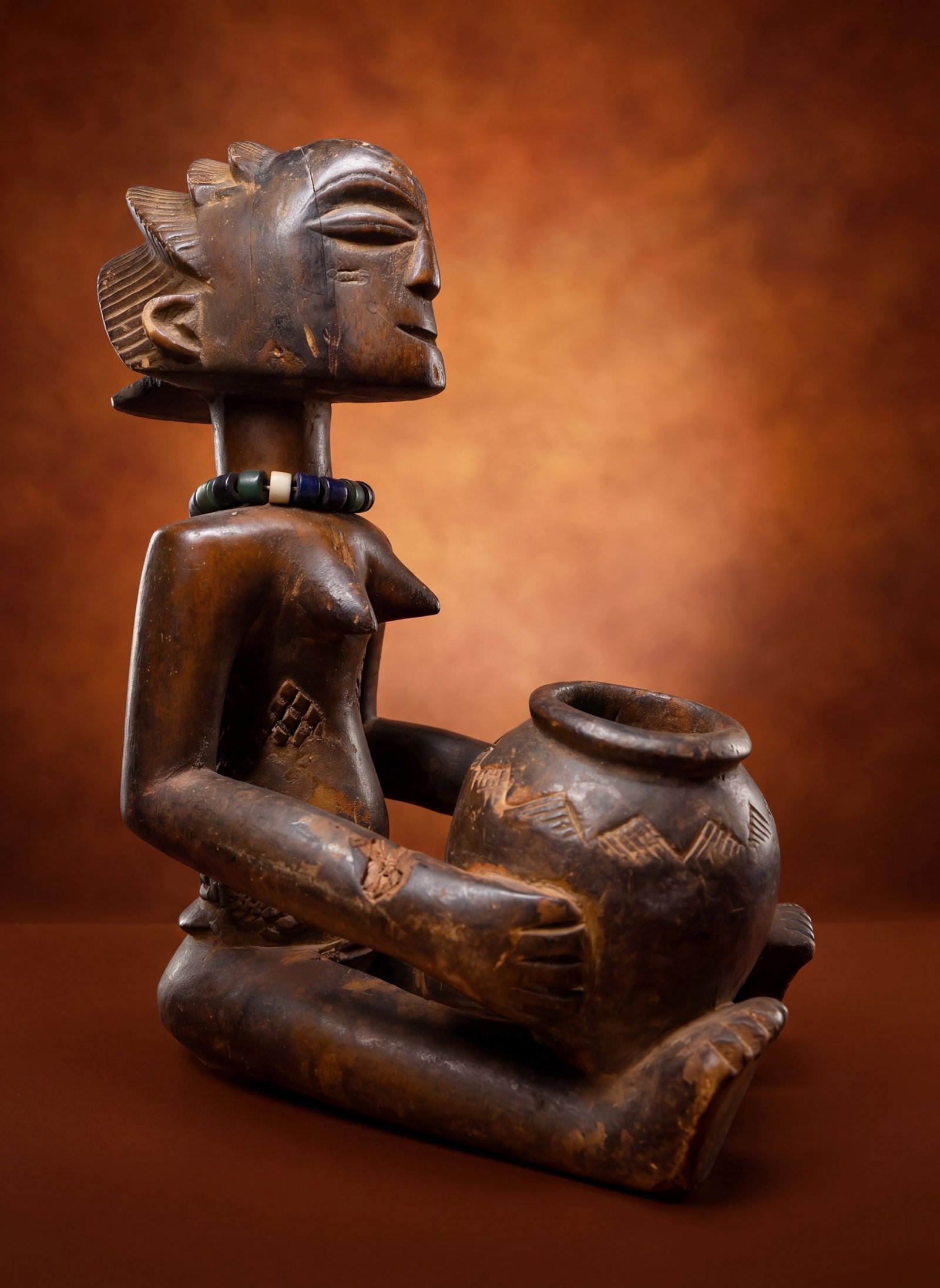 A Luba Mboko Bowl Bearer Sculpture: This is a finely carved old wooden female effigy of a sacred bowl-bearing figure created by the Luba peoples of the Democratic Republic of the Congo. Traditionally shaped as a kneeling or seated femal