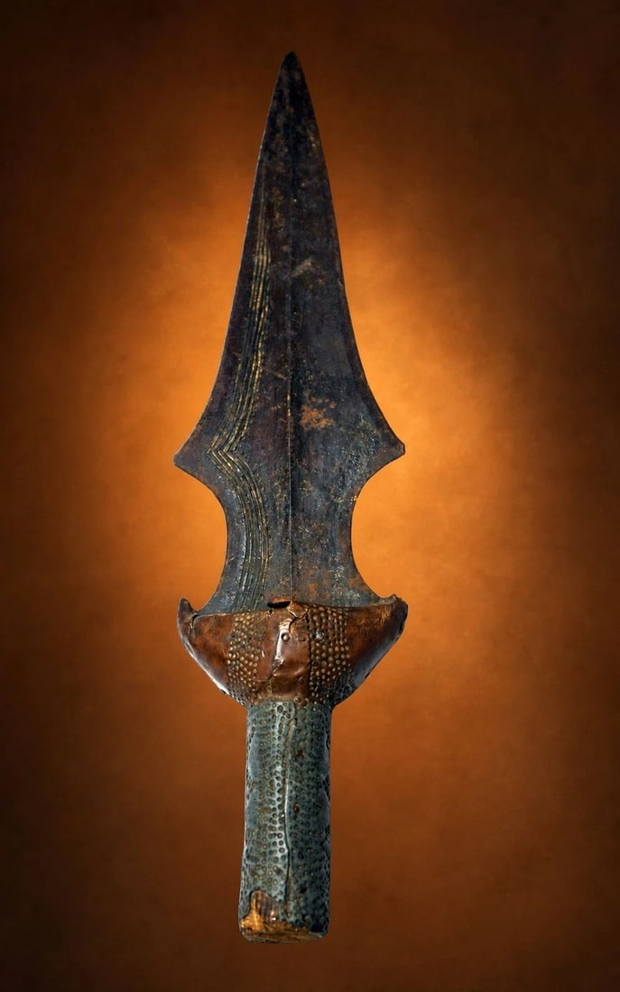 A Rare Tetela Dagger from Africa: A very old hand forged Iron dagger with incised metal work accented with well worn wooden handle covered in copper. The sword measures 12 inches long x 2.5 inches. Tetela peoples, Congo, Africa.