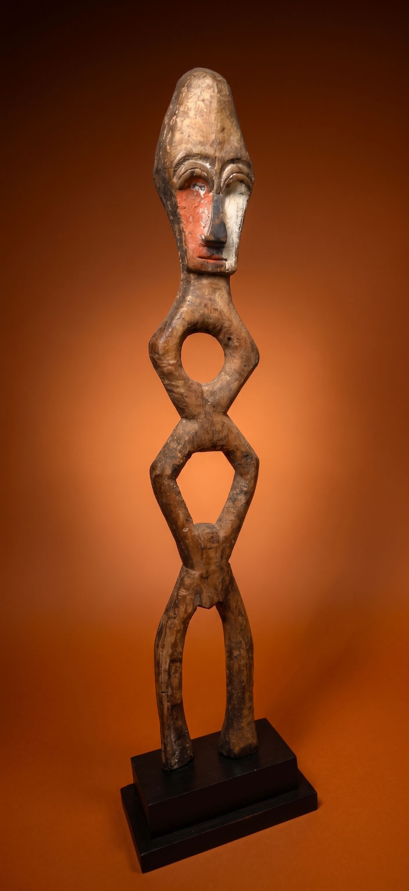 A Lengola Abstract Sculpture: A carved wooden ancestor spirit sculpture with a highly stylized / abstract form, carved eyes, painted face with contrasting colors and a well handled and worn surface. Lengola peoples, Congo, Africa.