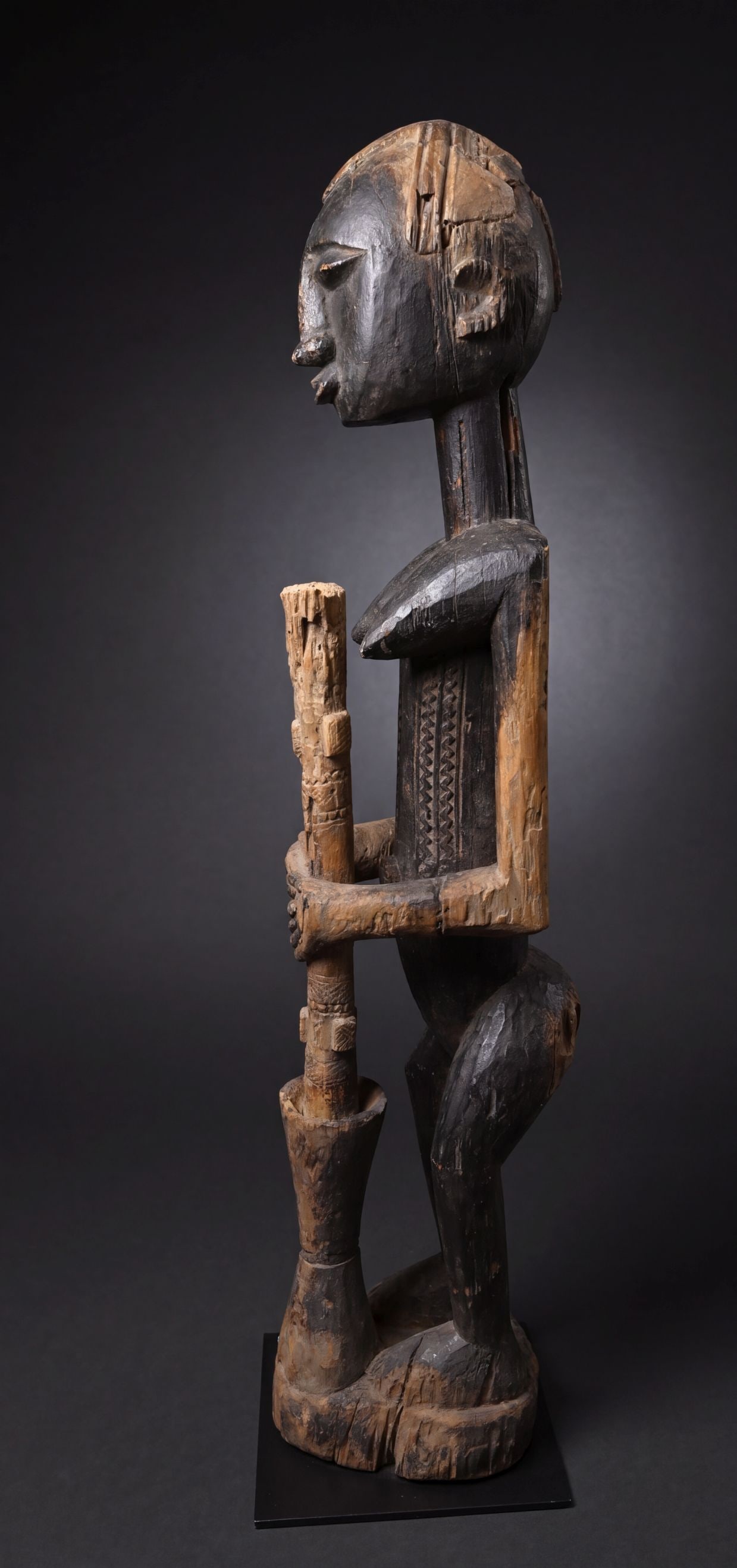 A Dogon Female Sculpture: Carved from a very heavy dense wood and shown working with a mortar and pestle /pounder, perhaps making Millet grain. The sculpture has wonderful incised linear designs and measures 37.5 inches tall x