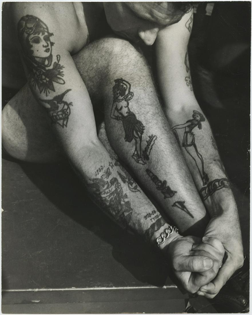 John Gutmann (1905-1998) "Tattooing. Sailor: John Gutmann (1905 Â– 1998) Â“Tattooing. SailorÂ’s Delight.Â” Tatoos on legs and arms, Honolulu. Vintage ferrotyped gelatin silver print on single weight paper, 1945, 9 3/8 x 7 ½ in