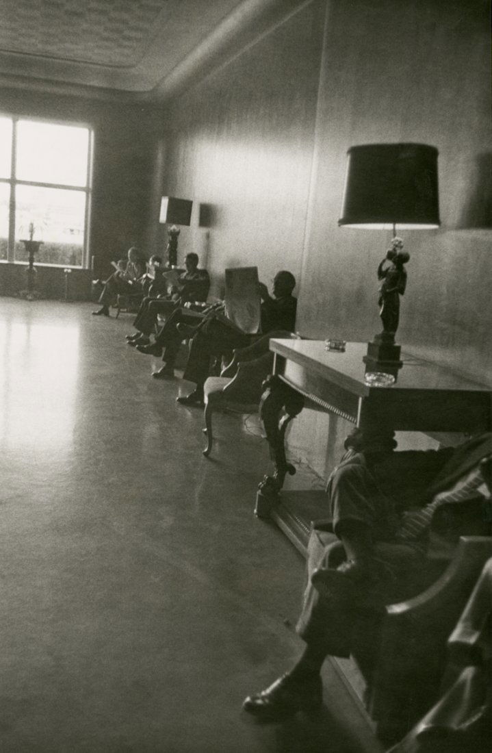 READING NEWSPAPERS IN A MEN'S CLUB, by ROBERT FRANK: READING NEWSPAPERS IN A MEN'S CLUB, by ROBERT FRANK. 13 7/8 x 11- inch gelatin silver print, ca 1955. “R.B.” in pencil on verso. Mild stain on upper margin. [3+]