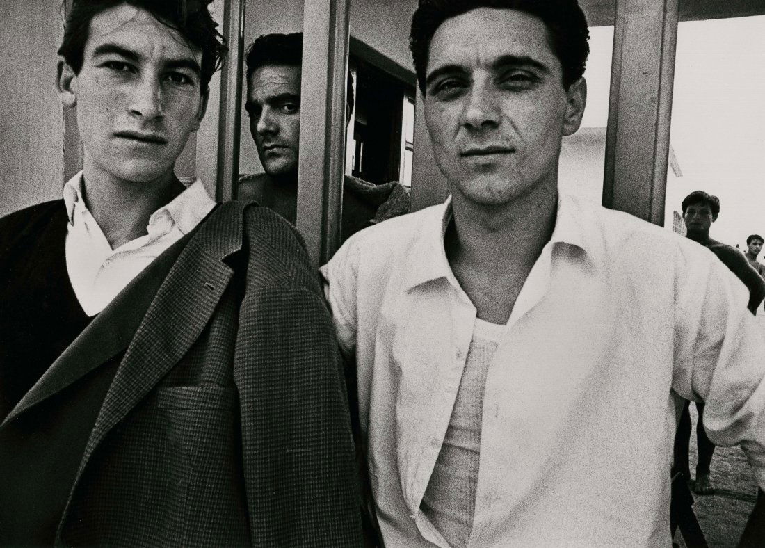 "ENTRANCE TO OSTIA BEACH ROME 1956" BY WILLIAM KLEIN.: "ENTRANCE TO OSTIA BEACH ROME 1956" BY WILLIAM KLEIN. 9 ¾ x 13 ¾- inch image on 12 x 16- inch paper, titled signed and dated 1981 on verso. Two Italian men with another peering through between.