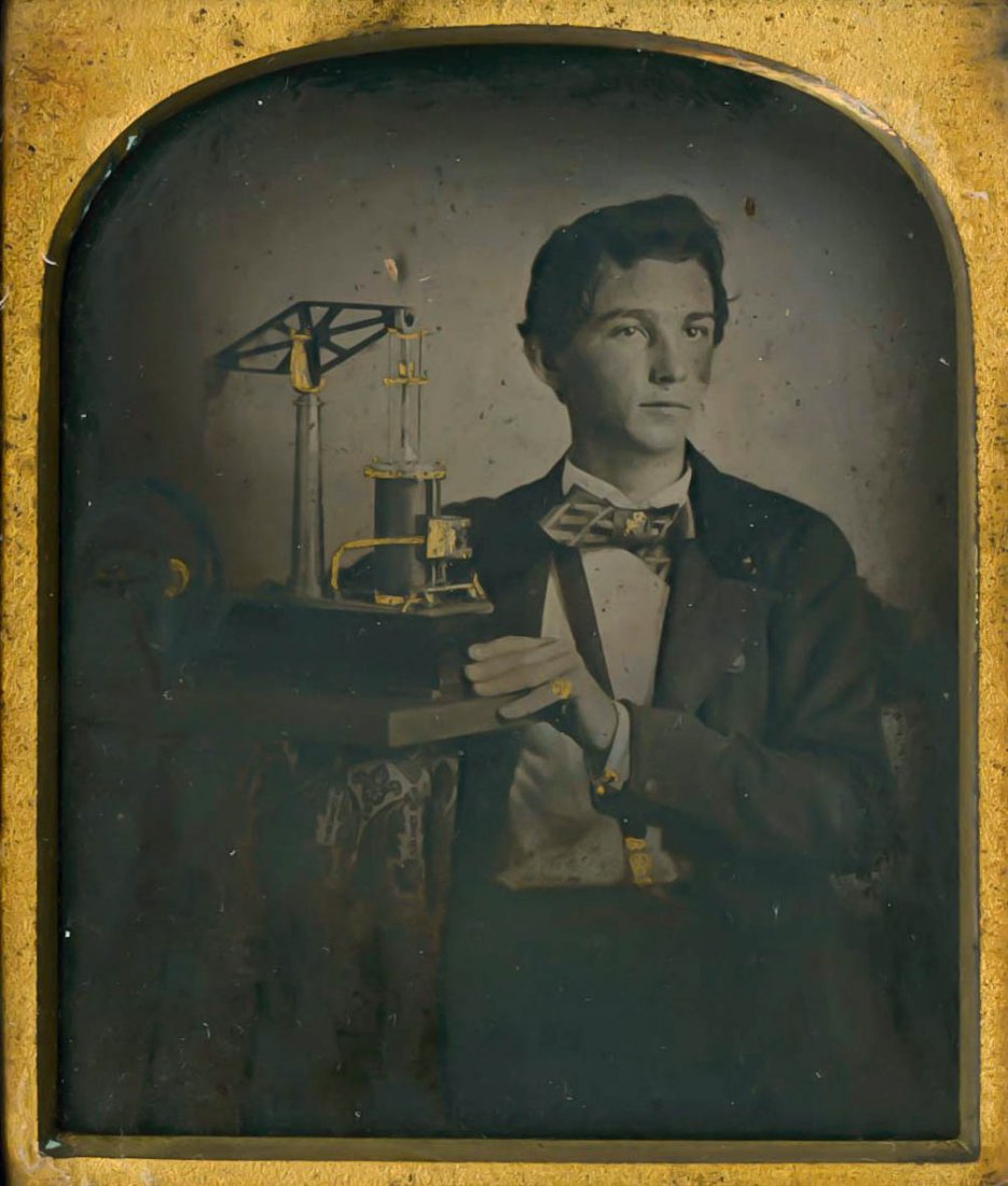 YOUNG INVENTOR WITH HIS INVENTION MODEL.: YOUNG INVENTOR WITH HIS INVENTION MODEL. This seems to be some kind of pump operated by electromagnetism. 1/6 plate ambrotype. Dark and the bottom and left side, but no damage. Some details are gilded