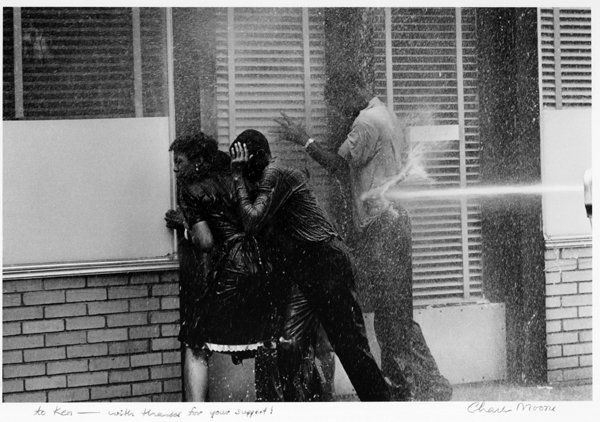 CHARLES MOORE, FIRE HOSES AGAINST BIRMINGHAM STUDENT: CHARLES MOORE, FIRE HOSES AGAINST BIRMINGHAM STUDENT. 8 x 12- inch image on 11 x 14- inch sheet, signed on the bottom margin with dedication. These photographs of “Bull” Connors’ police force us