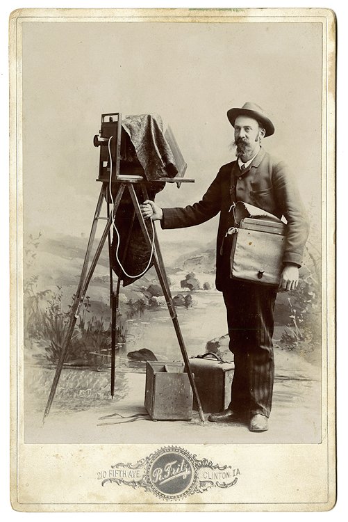Photographing out in the field.: Photographing out in the field. There are two plate boxes on the ground. The photographer holds a bag (for exposed plates?) This is a particularly beautiful photograph. Cabinet card by Fritz, Clinton,