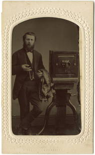 A photographer with his camera.: A photographer with his camera. He holds the bulb and cloth. CDV size tintype.