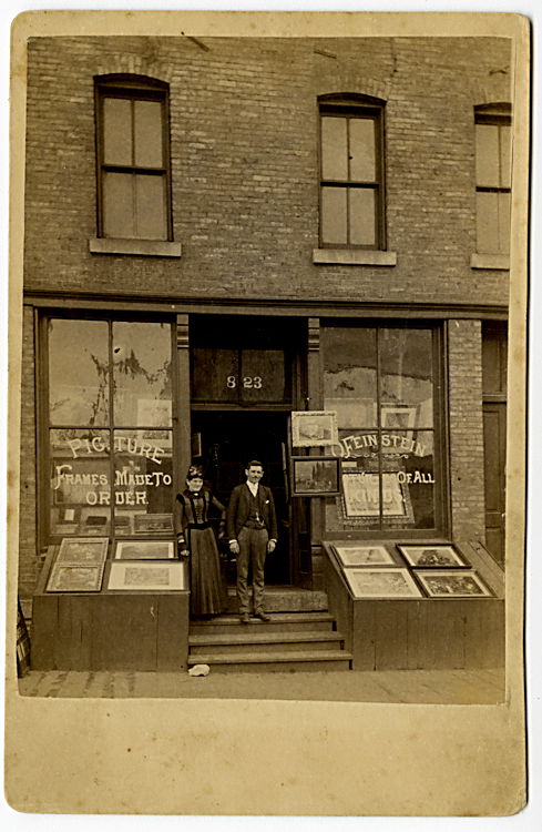 O. Feinstein ”Pictures of All Kinds,” “Picture Frames: O. Feinstein ”Pictures of All Kinds,” “Picture Frames Made to Order.” This is the exterior of their shop in Minnesota [pen verso], with the proprietor on the front steps. Cabinet by Acme View