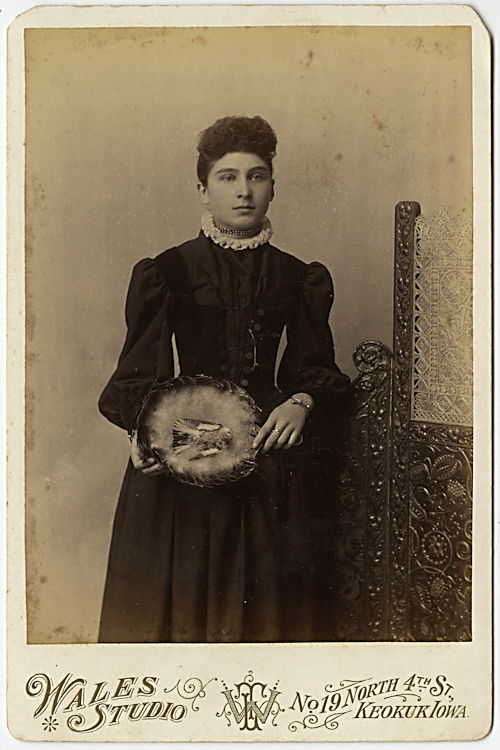 A woman holds a basket with a dead bird in it.: A woman holds a basket with a dead bird in it. By Wales Studio, Keokuk, Iowa. The upper mount corners are slightly clipped.
