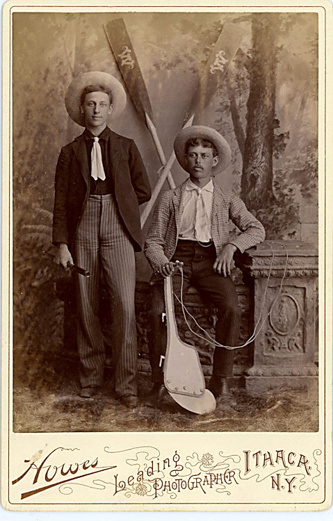 A collegiate rowing crew.: A collegiate rowing crew. One holds a rudder and there are oars with a “W” on them. By Howes, Ithaca, NY. These may be visitors to Cornell from Wesleyan.