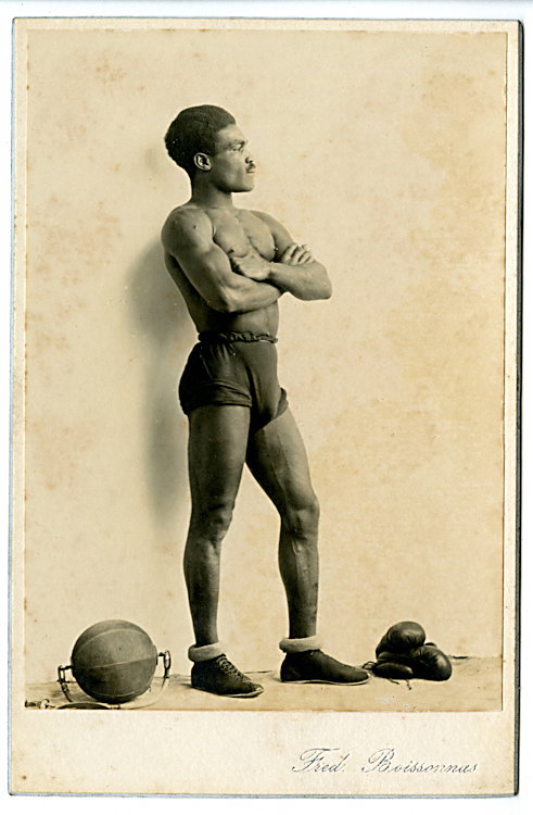 A fit boxer with his gloves and training ball.: A fit boxer with his gloves and training ball. A fine profile by Fred. Boissonnas, the Swiss photographer most celebrated for his photographs of Greece.
