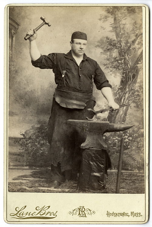 A blacksmith.: A blacksmith. A great image with an appropriate backdrop. Moving the anvil into the studio must have been quite a job. By Lane Brothers, “Berkshire Photographic Studio/ Portrait House” Hoosatonic,