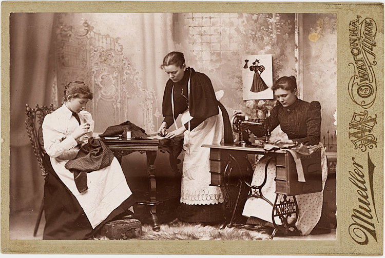 Making clothing.: Making clothing. Women perform 3 activities: hand sewing, cutting, and sewing on a “Domestic” sewing machine. A fashion illustration is put up on the backdrop. Cabinet card by Mueller, Owatonna, M