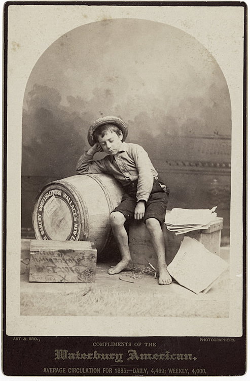 A newspaper boy dozes against a barrel of flour.: A newspaper boy dozes against a barrel of flour. The photograph is by Adt & Brother, Waterbury, Connecticut. The cabinet card was distributed compliments of the Waterbury American.