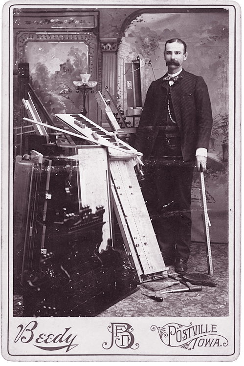 An organ builder or repair man.: An organ builder or repair man. The keyboard and other elements are piled in a heap. By Reedy, Postville, Iowa.