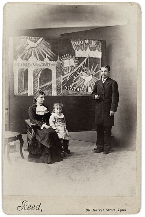 An artist Evangelist.: An artist Evangelist. A label on the verso identifies the subject as “Rev. J. E. Cross, Artist Evangelist and Family. Lynn, Mass.” The mural he painted is angled against the backdrop. The child se